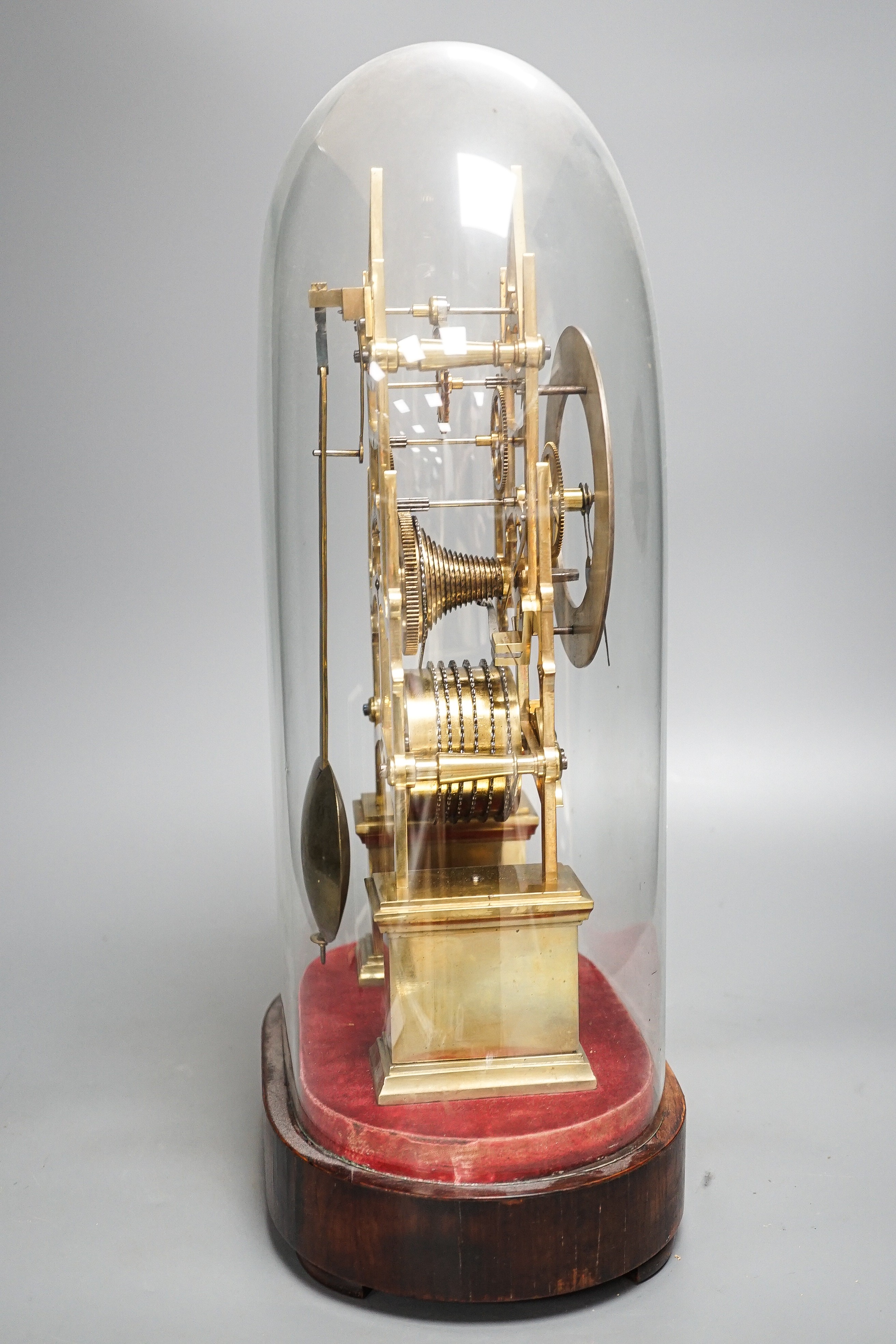 A Victorian brass skeleton clock, with single fusee movement, under a glass dome 43 cms high.